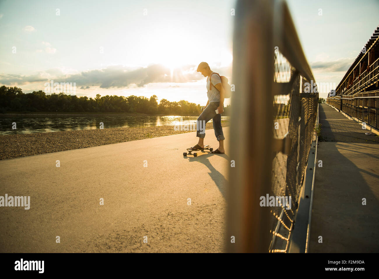 Uomo con lo skateboard al crepuscolo serale Foto Stock