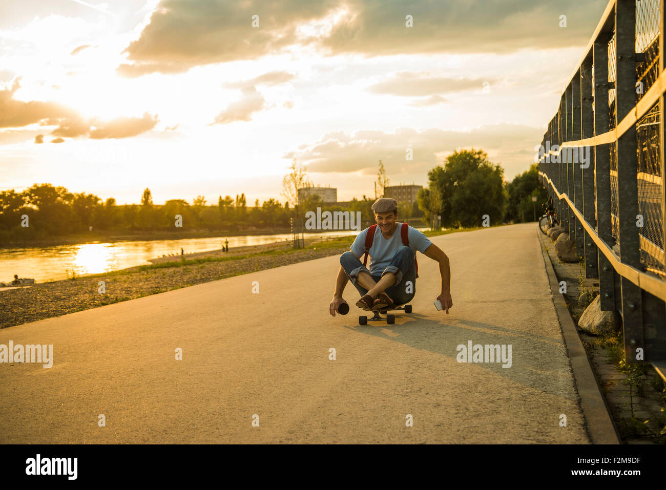 Uomo seduto su skateboard nel crepuscolo della sera Foto Stock