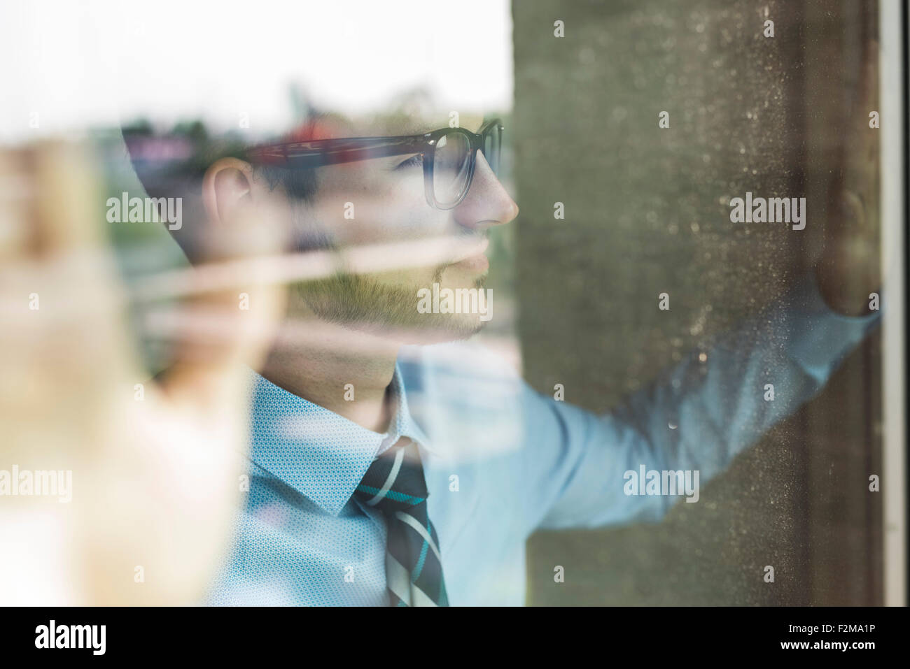 Giovane imprenditore guardando fuori della finestra Foto Stock