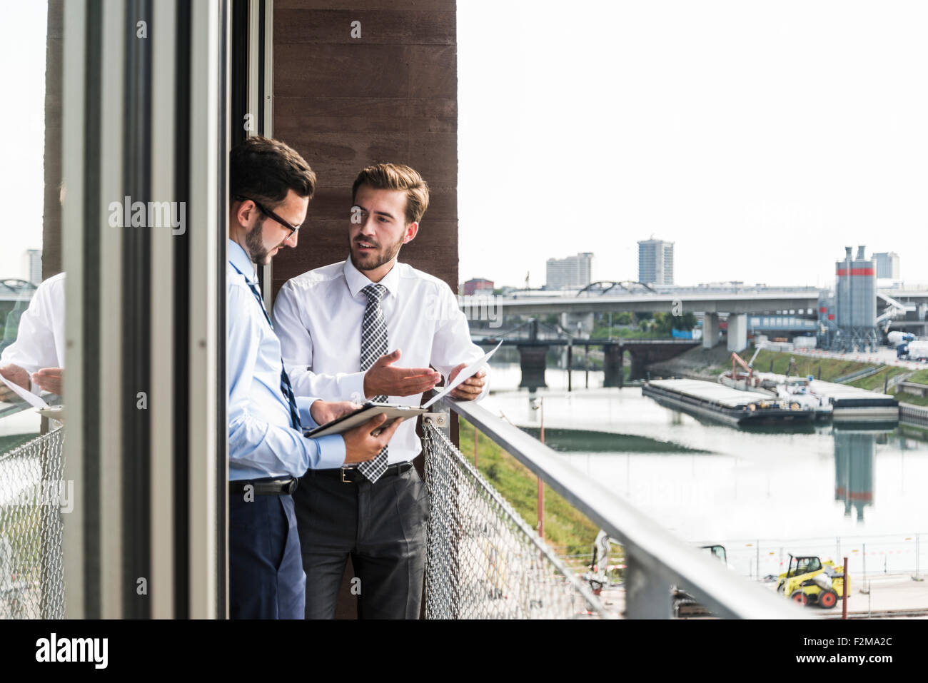 Due giovani imprenditori con documenti e tavoletta digitale discutendo sul balcone Foto Stock