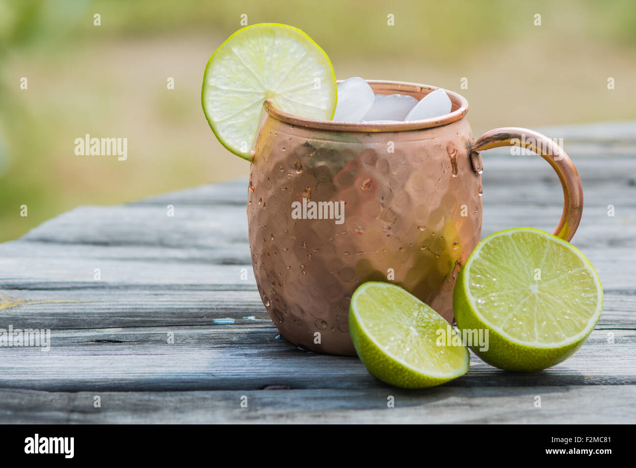 Il rame mug seduti su un tavolo di legno guarnito con fettina di lime e cunei Foto Stock