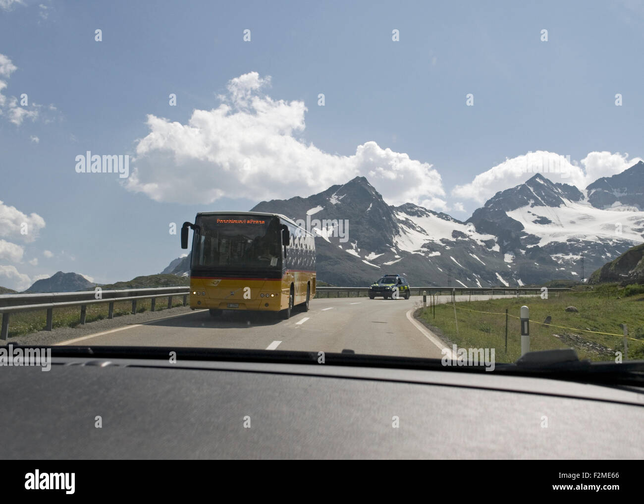 I mezzi di trasporto pubblico bus sulla strada di montagna visto da un auto nei pressi del confine tra Svizzera e Italia nel cantone dei Grigioni Foto Stock