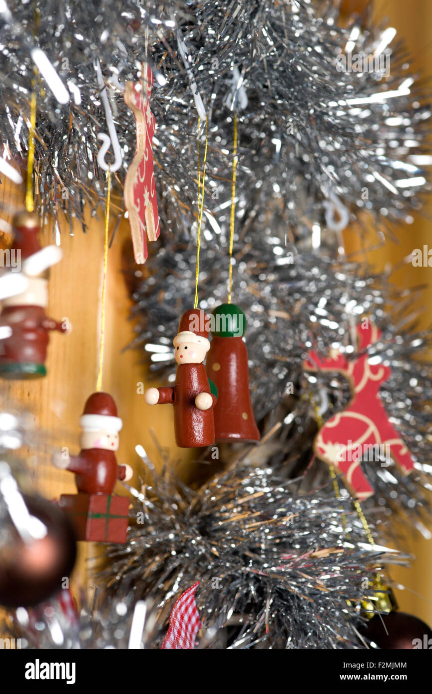 Chiudere fino a una serie di divertenti e simpatici figure in legno pendenti da un'argentea tinsel laden decorazione di Natale Foto Stock