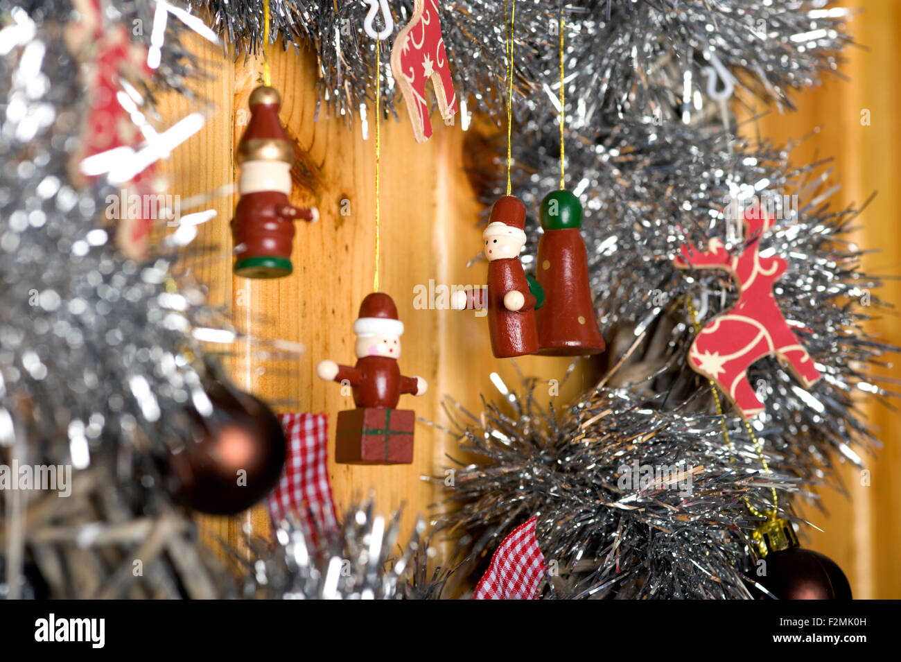 Chiudere fino a una serie di divertenti e simpatici figure in legno pendenti da un'argentea tinsel laden decorazione di Natale Foto Stock