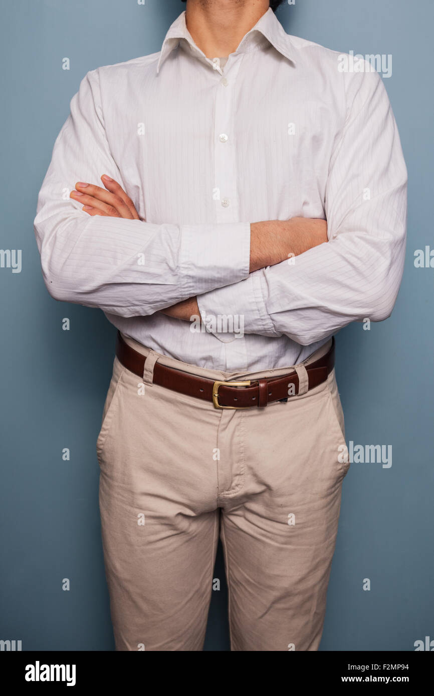 Giovane uomo in piedi da una parete blu con le braccia incrociate Foto Stock