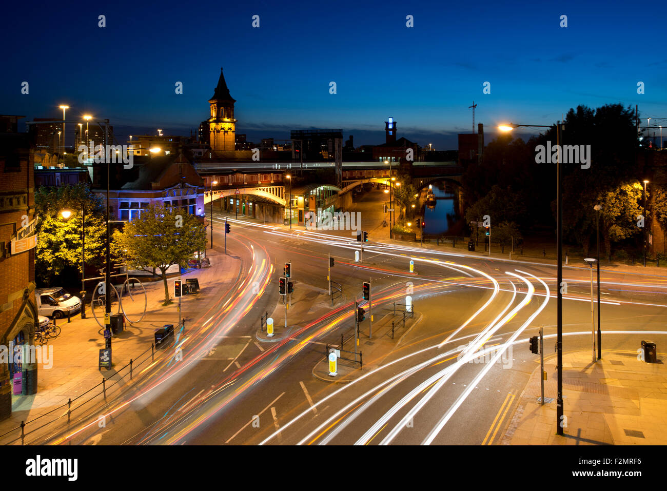 Sentieri di luce del traffico in movimento in corrispondenza della giunzione di Whitworth Street West e Deansgate Manchester centro città di notte. Foto Stock