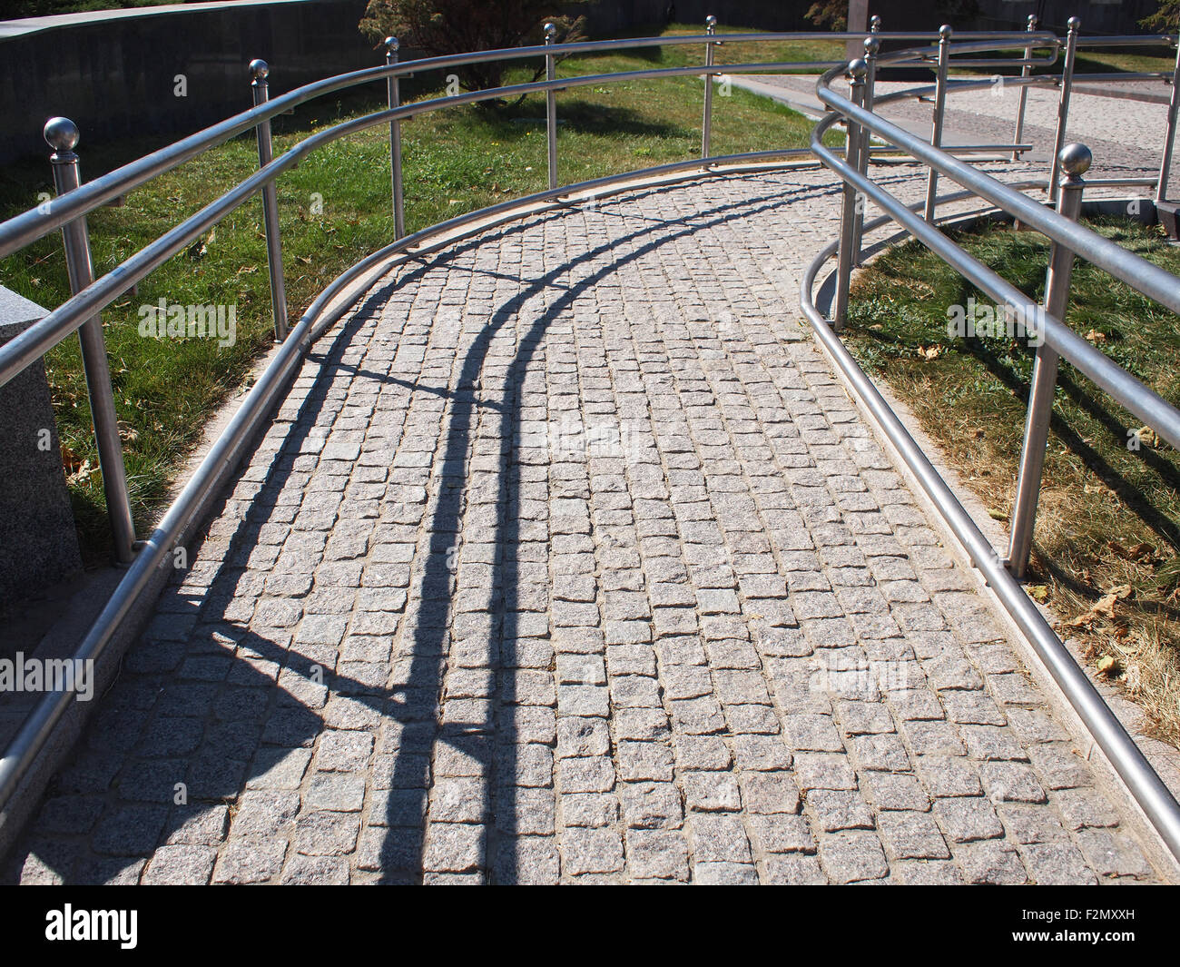 Rampa per disabili dal pavimento di granito su una soleggiata giornata estiva con ombre di mezzogiorno Foto Stock