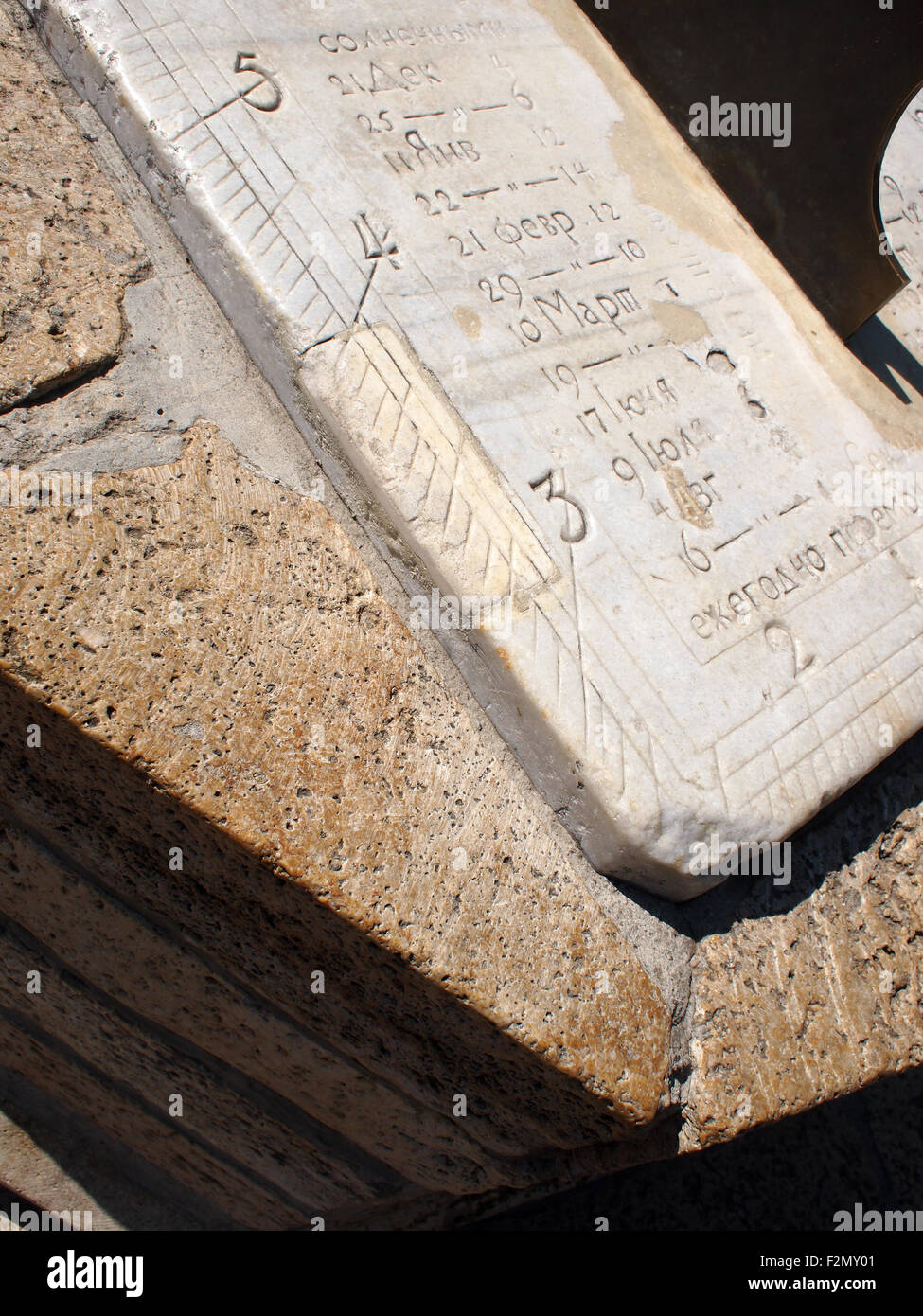 Frammento di pietra antica meridiana quadrante closeup. Sulla lastra di marmo bianco incisi i nomi e i numeri dei mesi in russo Foto Stock