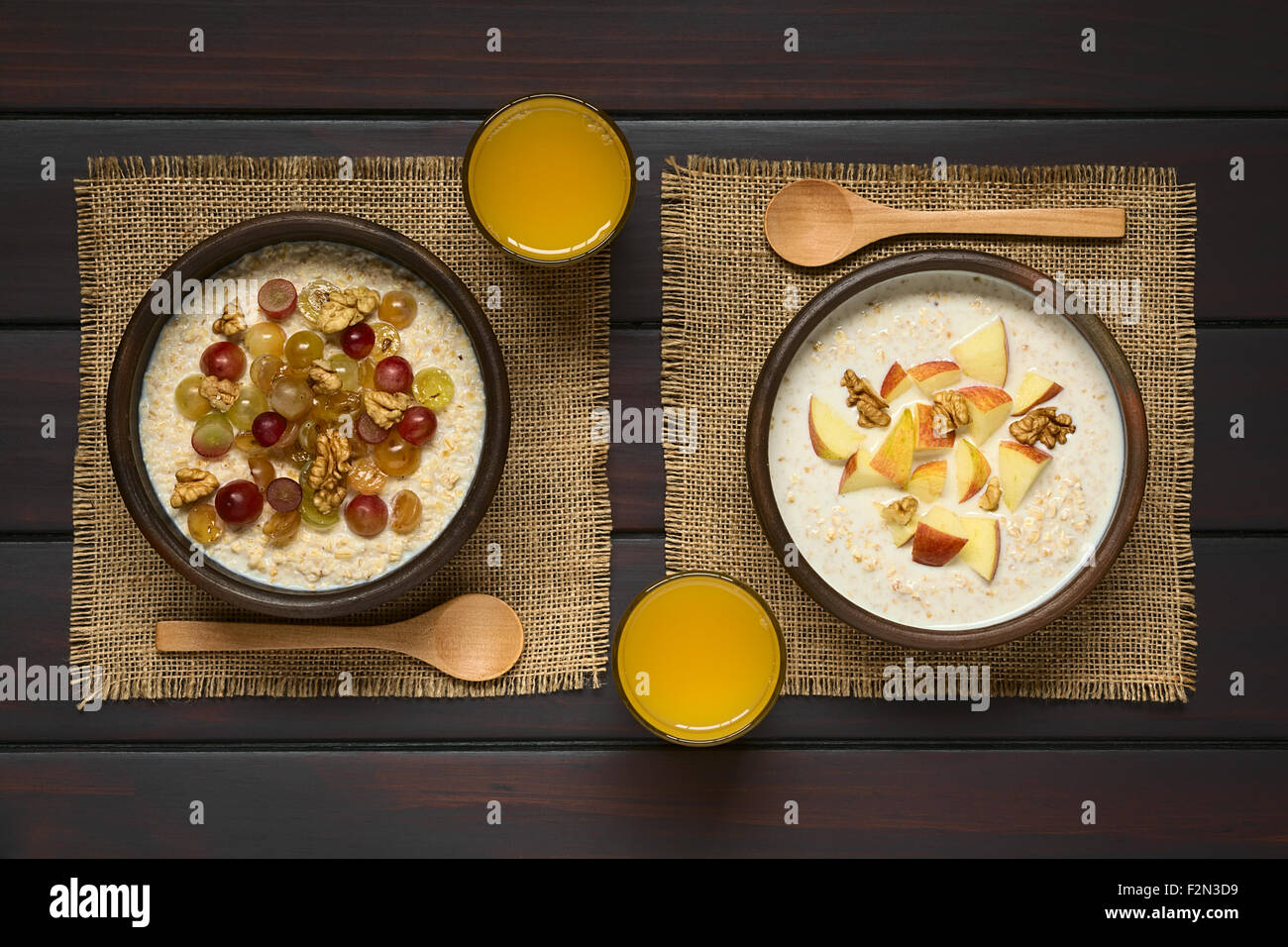 Farina di avena porridge con uva, mele e noci in ciotole rustiche, bicchiere di succo di frutta e il cucchiaio di legno sul lato Foto Stock