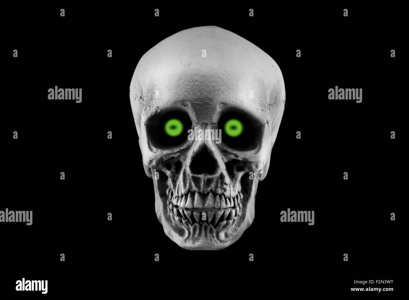 Un cranio di Halloween decorazione con occhi verdi isolati su uno sfondo nero Foto Stock