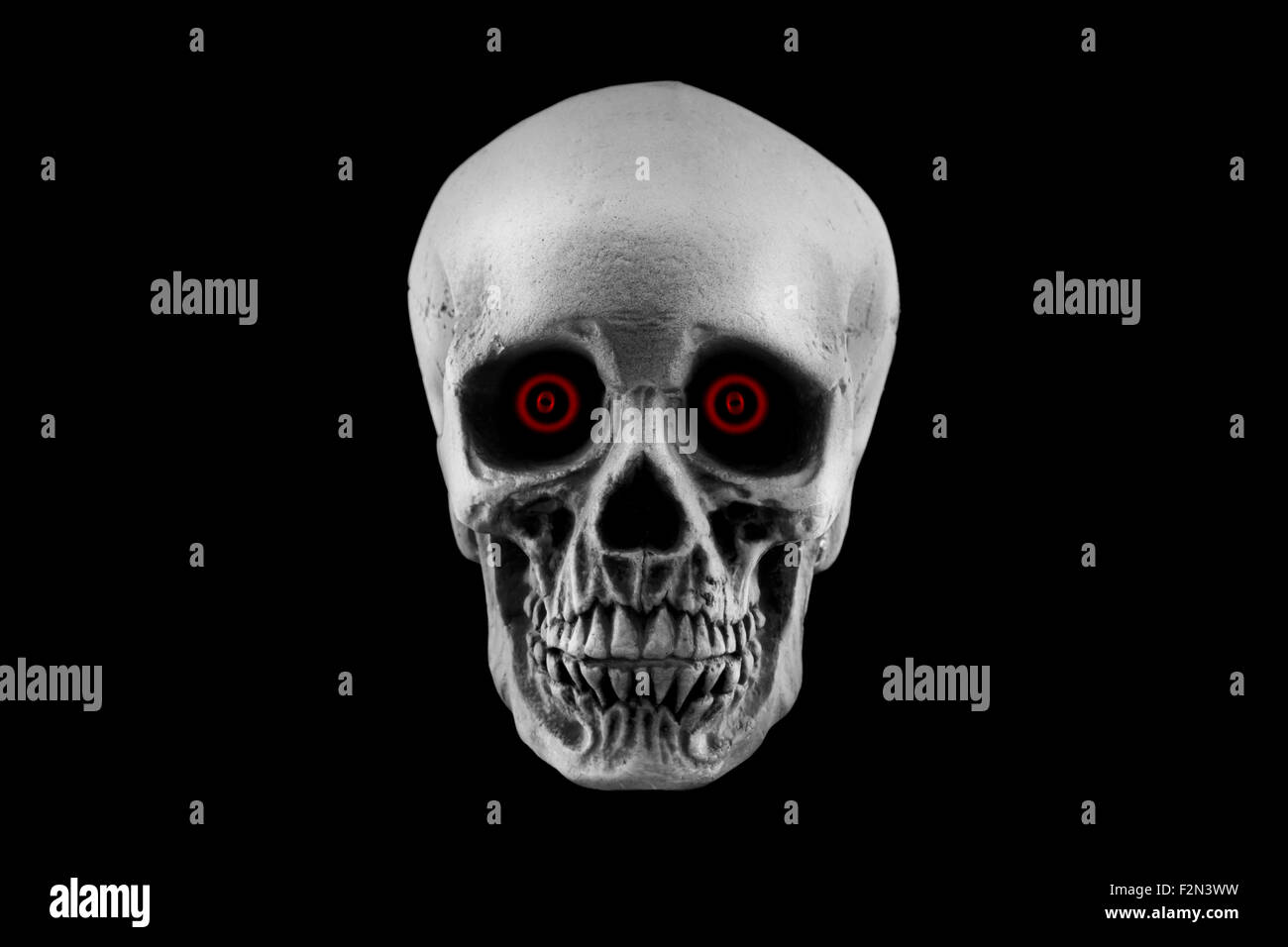 Un cranio di Halloween decorazione con occhi rossi isolato su sfondo nero Foto Stock