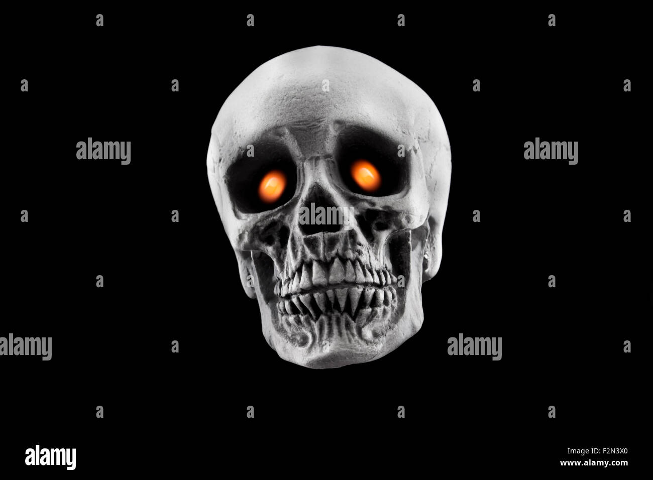 Un cranio di Halloween decorazione con gli occhi gialli isolati su uno sfondo nero Foto Stock