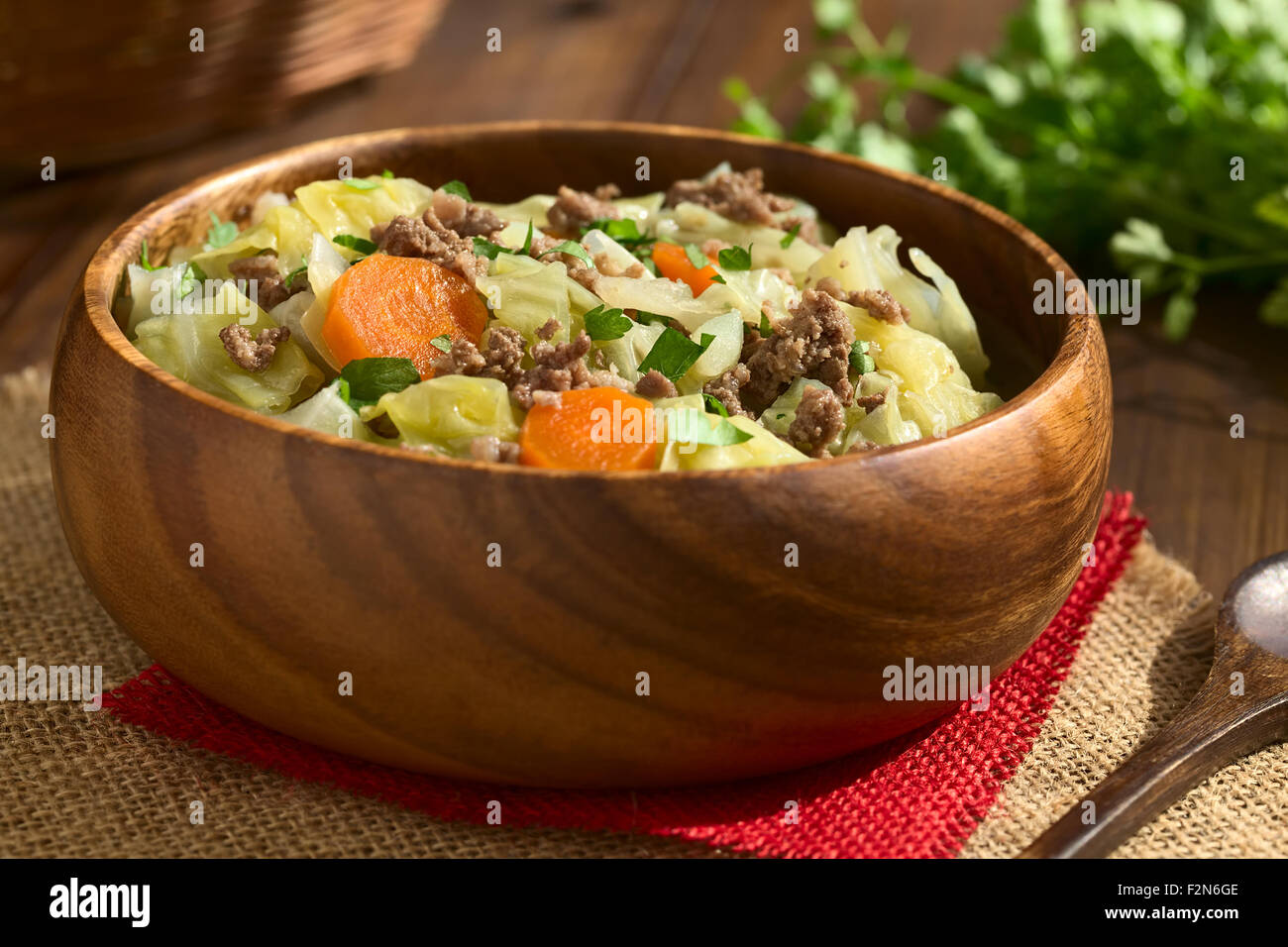 Verze, carote, patate e lo stufato di carne macinata o minestra con il prezzemolo nel recipiente di legno Foto Stock