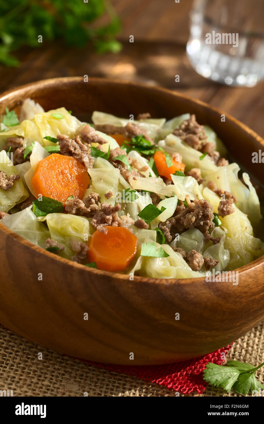 Verze, carote, patate e lo stufato di carne macinata o minestra con il prezzemolo nel recipiente di legno Foto Stock