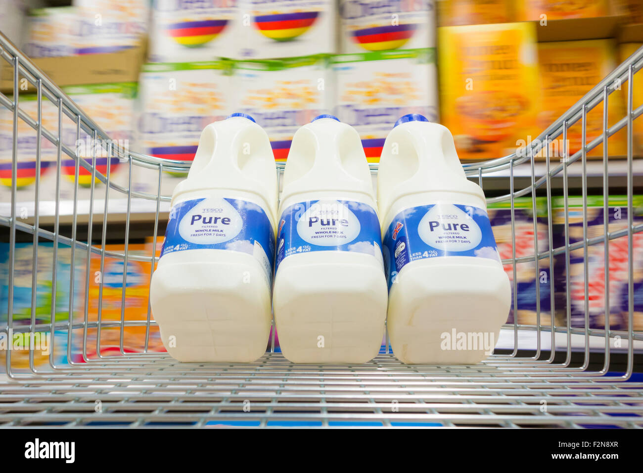 Il latte nel carrello della spesa in Tesco supermaket. Regno Unito. Sfocato cereali da prima colazione in background Foto Stock