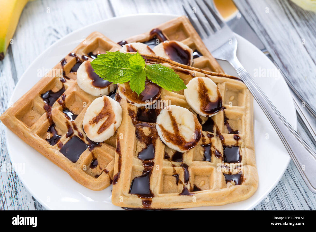 Tavolo per la colazione (cialde con banane e salsa al cioccolato come close-up shot) Foto Stock