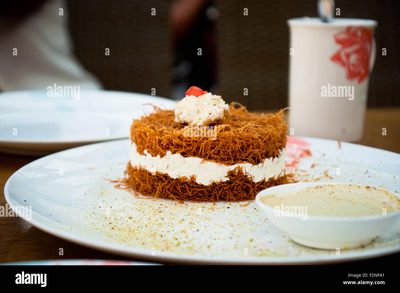 Un semplicemente delizioso dessert libanese servita con syrop, che mescola che dolce, vermicelli croccanti bite con crema soffice e lasciare Foto Stock