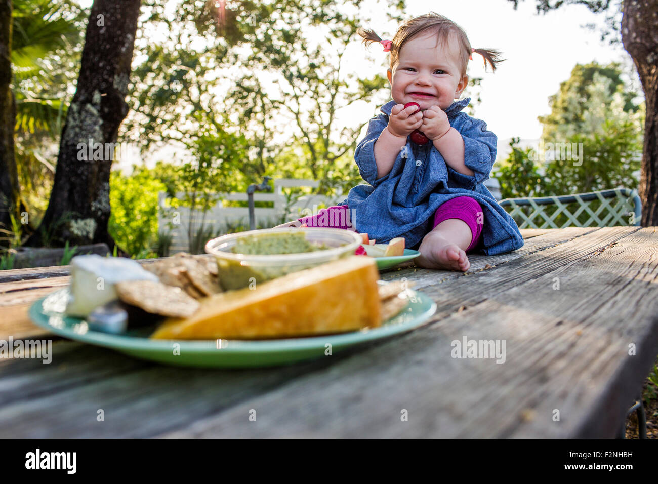 Caucasian baby ragazza seduta sul patio tabella Foto Stock