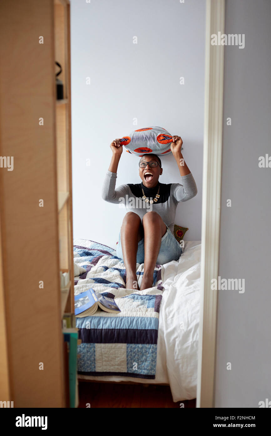 Razza mista donna giocando con il cuscino sul letto Foto Stock
