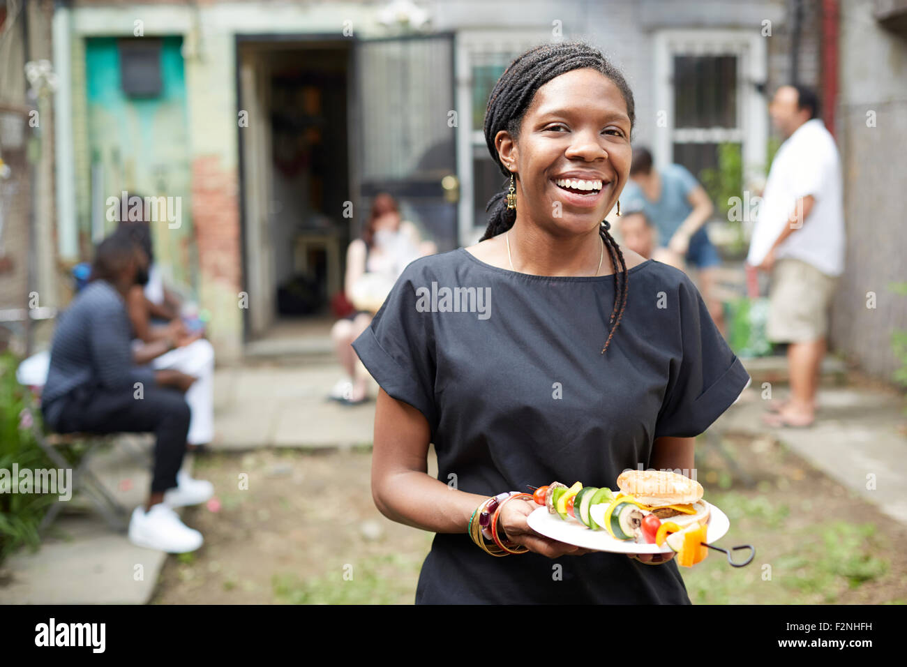 African American donna di mangiare al barbecue nel cortile Foto Stock