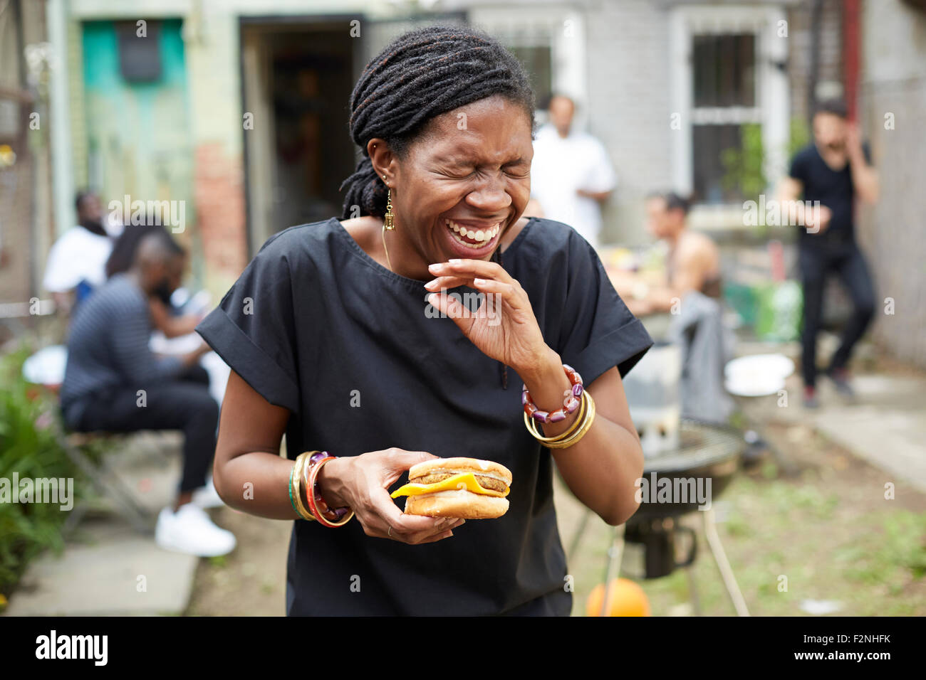 African American donna di mangiare al barbecue nel cortile Foto Stock