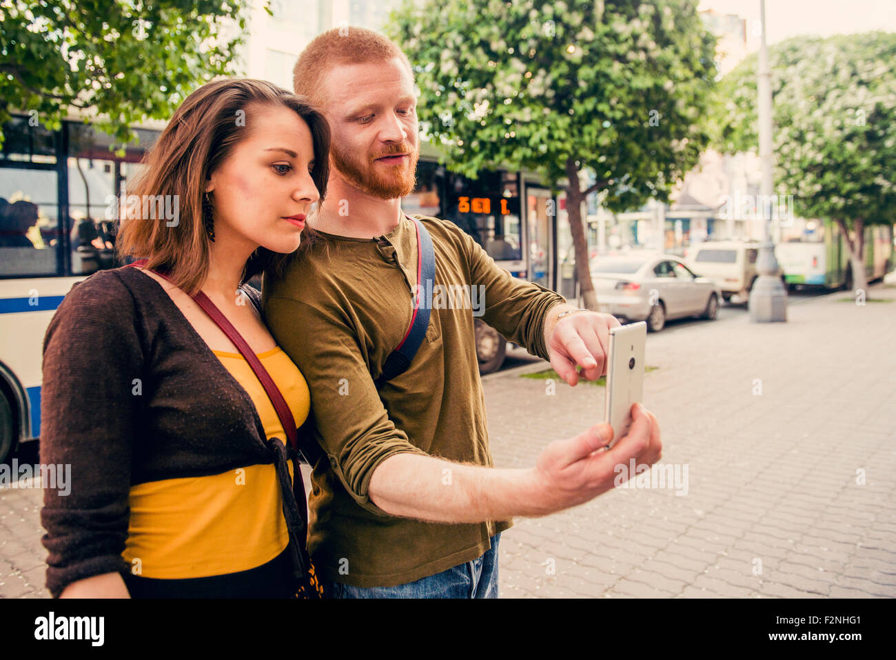Coppia caucasica tramite telefono cellulare sul marciapiede della città Foto Stock