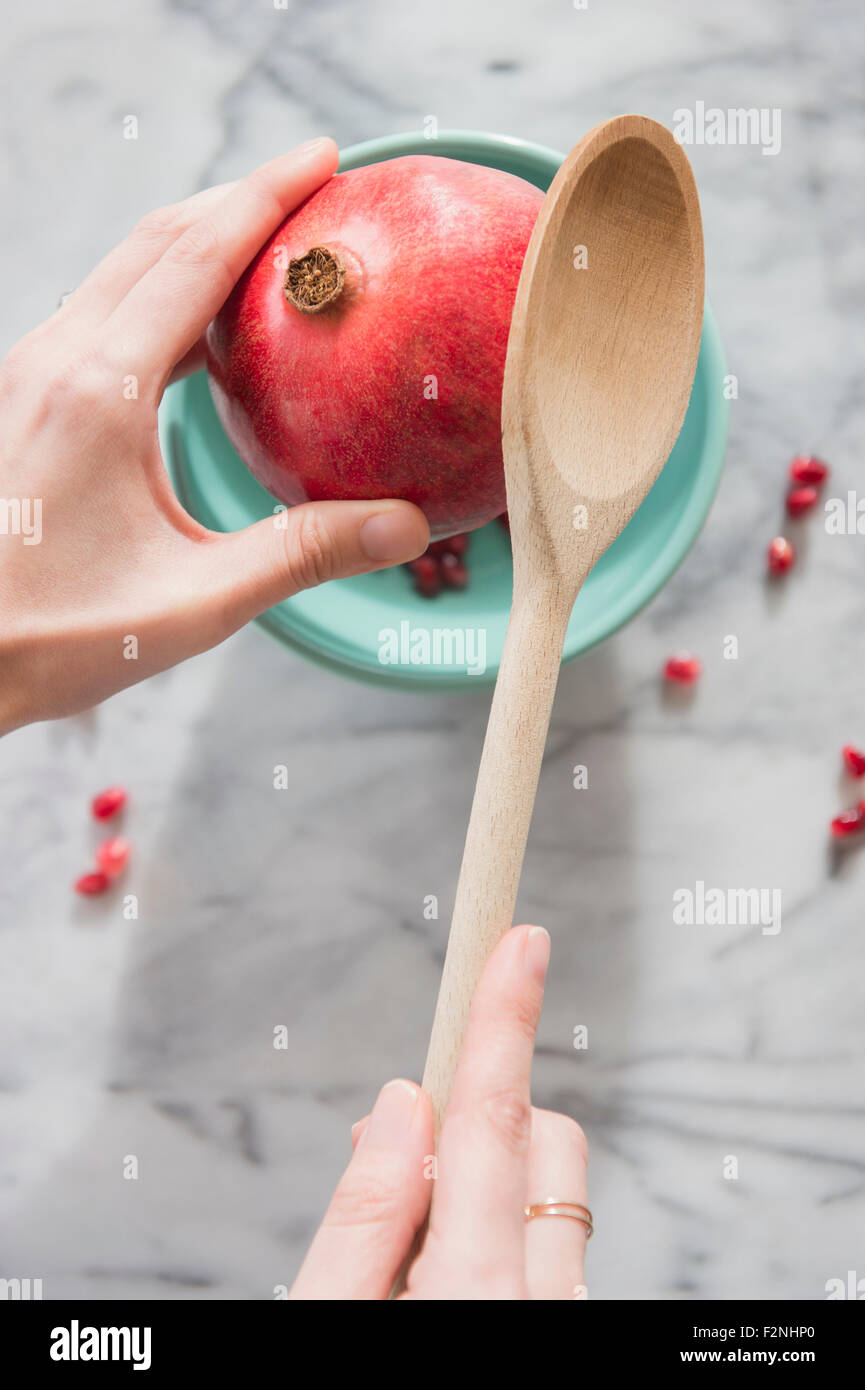 Stretta di mano il melograno di cracking con cucchiaino Foto Stock