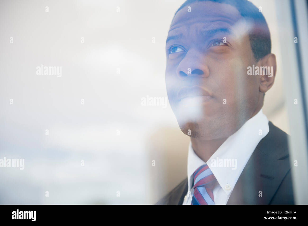 Imprenditore a guardare fuori dalla finestra di ufficio Foto Stock