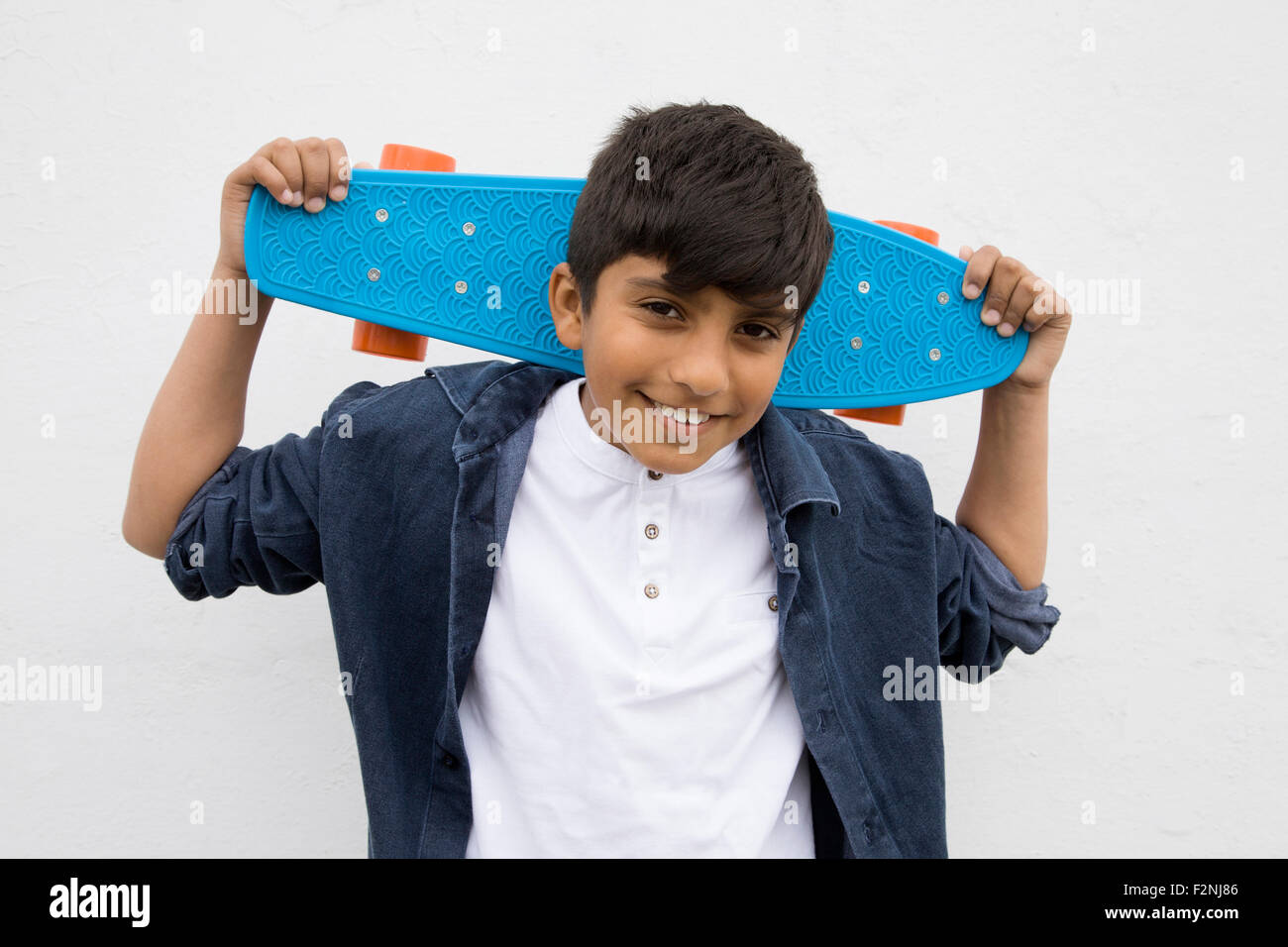 Asian boy holding skateboard Foto Stock