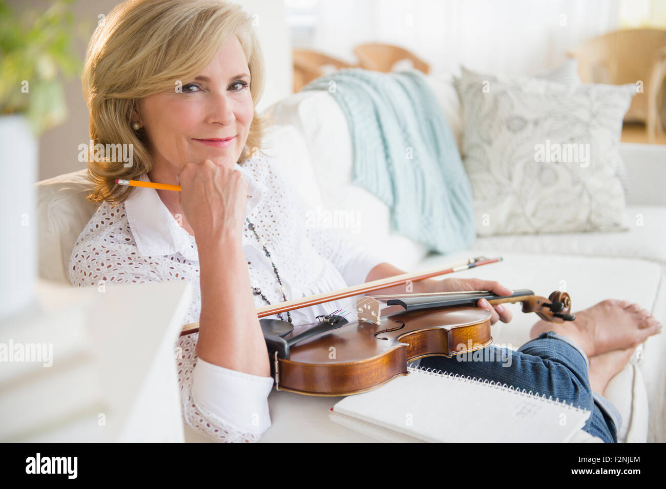 La donna caucasica holding violino sul divano Foto Stock