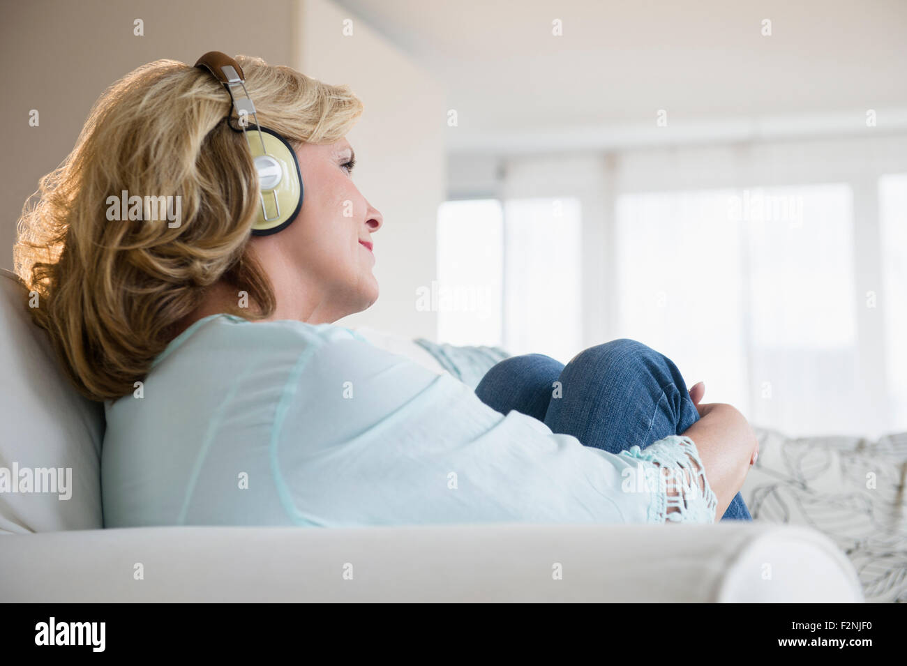La donna caucasica ascoltando le cuffie sul divano Foto Stock
