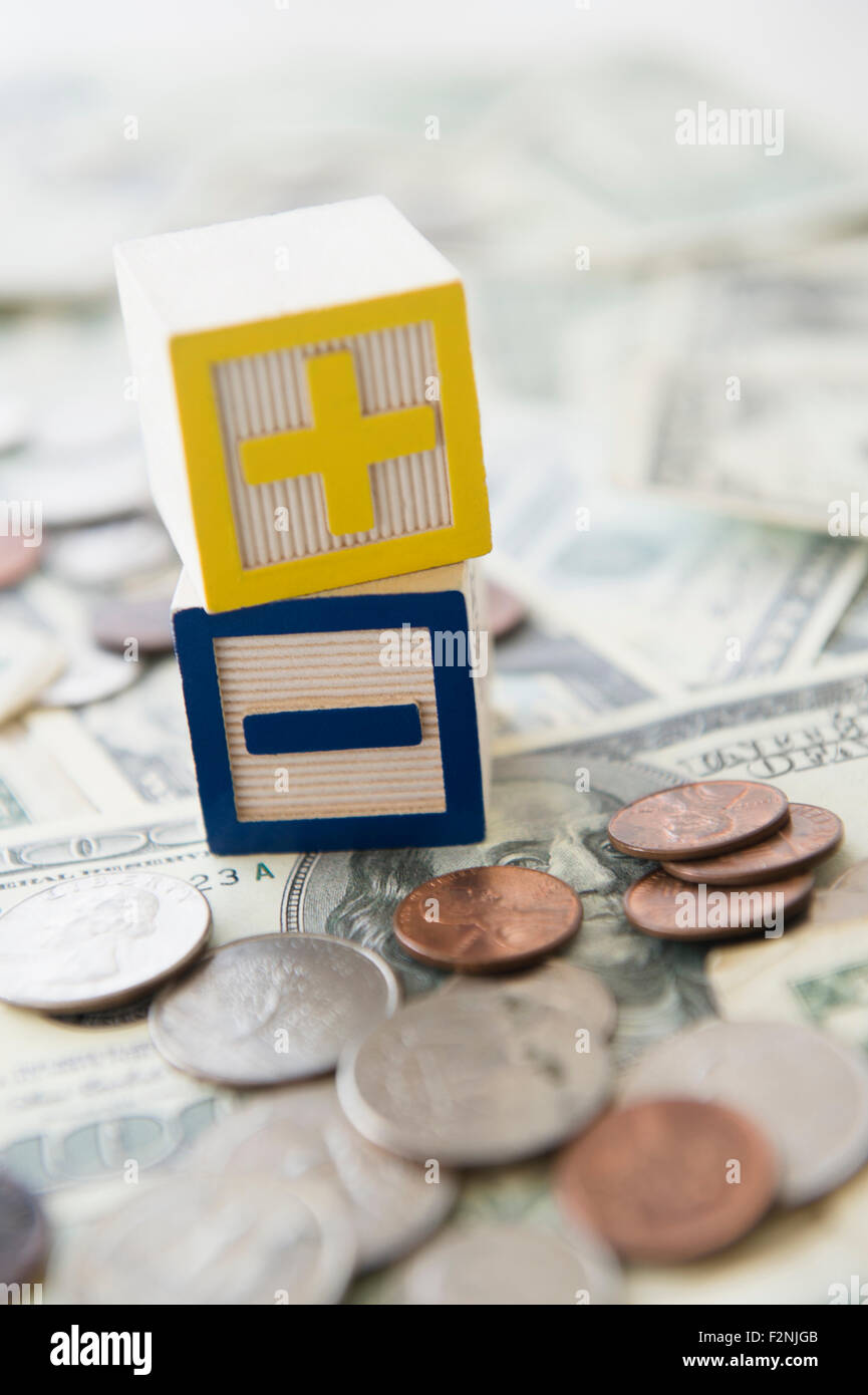 Close up di più e meno blocchi giocattolo con denaro Foto Stock