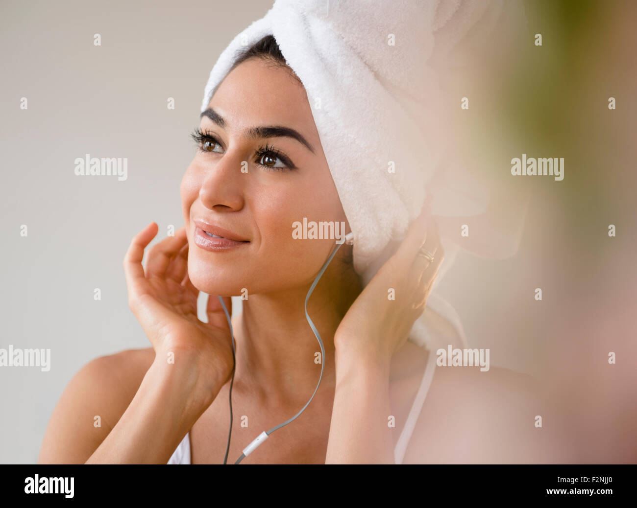 Donna con capelli in ascolto di asciugamani per cuffie Foto Stock