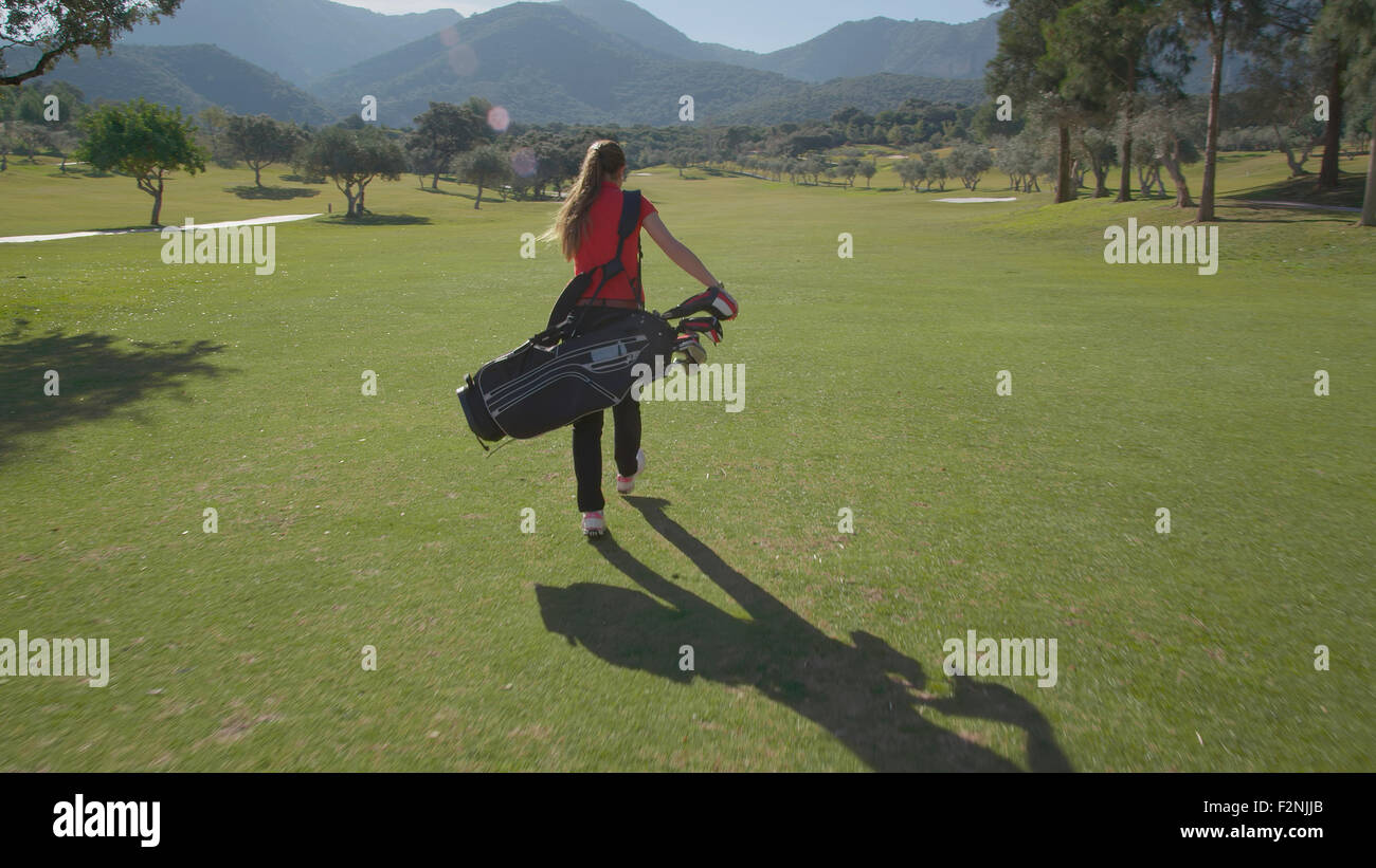La donna caucasica portando borsa da golf sul corso Foto Stock