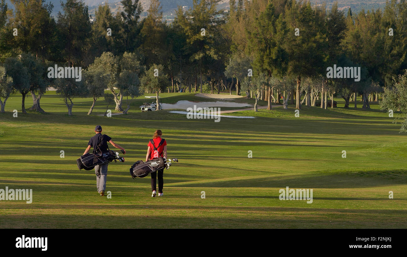 Coppia caucasici che trasportano le sacche da golf sul corso Foto Stock