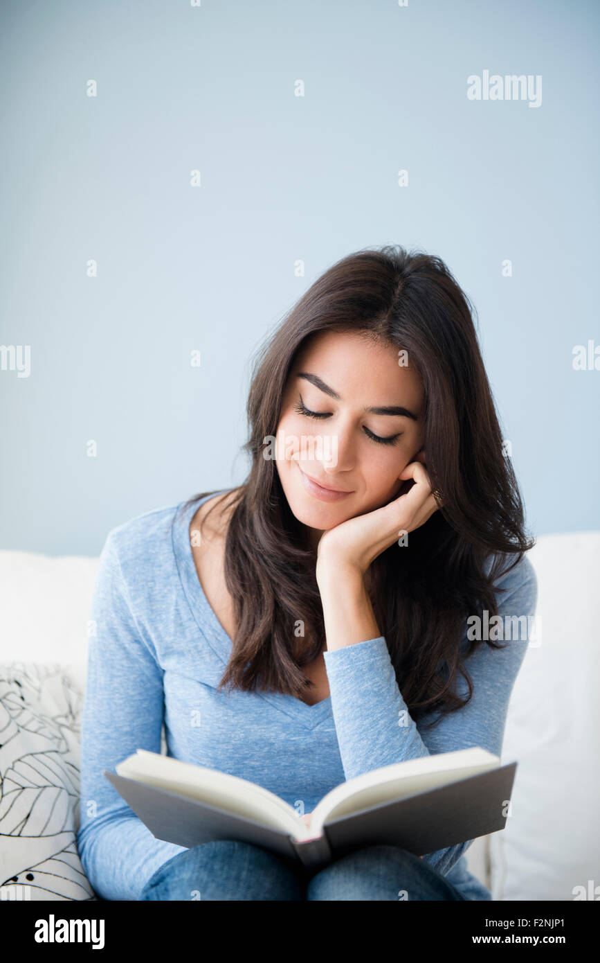 Close up della donna la lettura di un libro sul divano Foto Stock