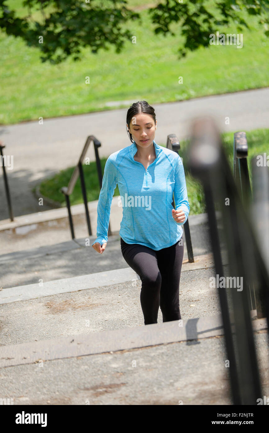 Donna ispanica jogging sulle fasi della città Foto Stock