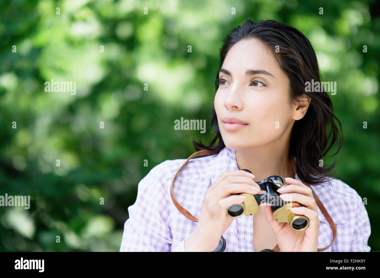 Donna ispanica usando il binocolo all'aperto Foto Stock