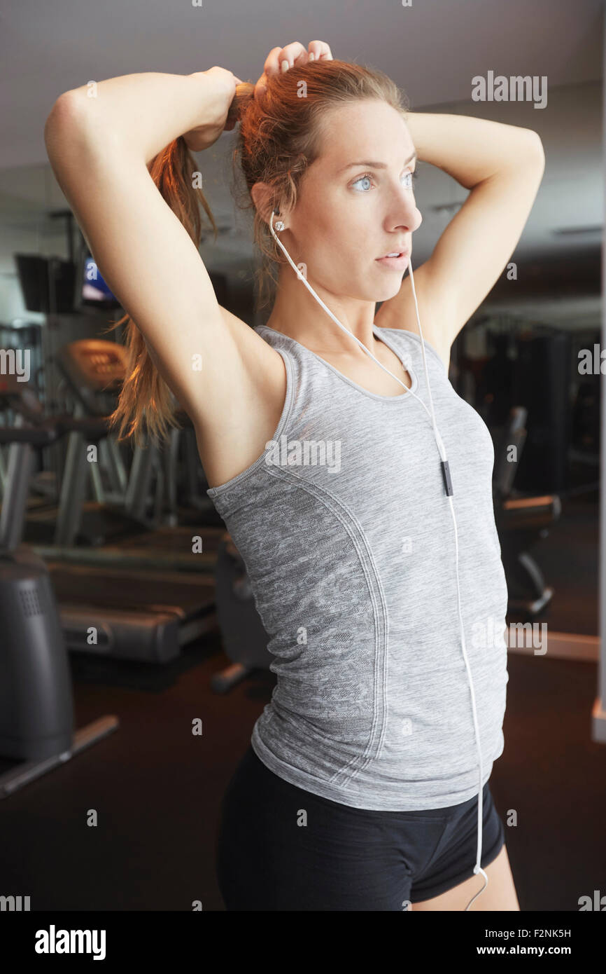 Donna capelli di legatura in coda di cavallo in palestra Foto Stock