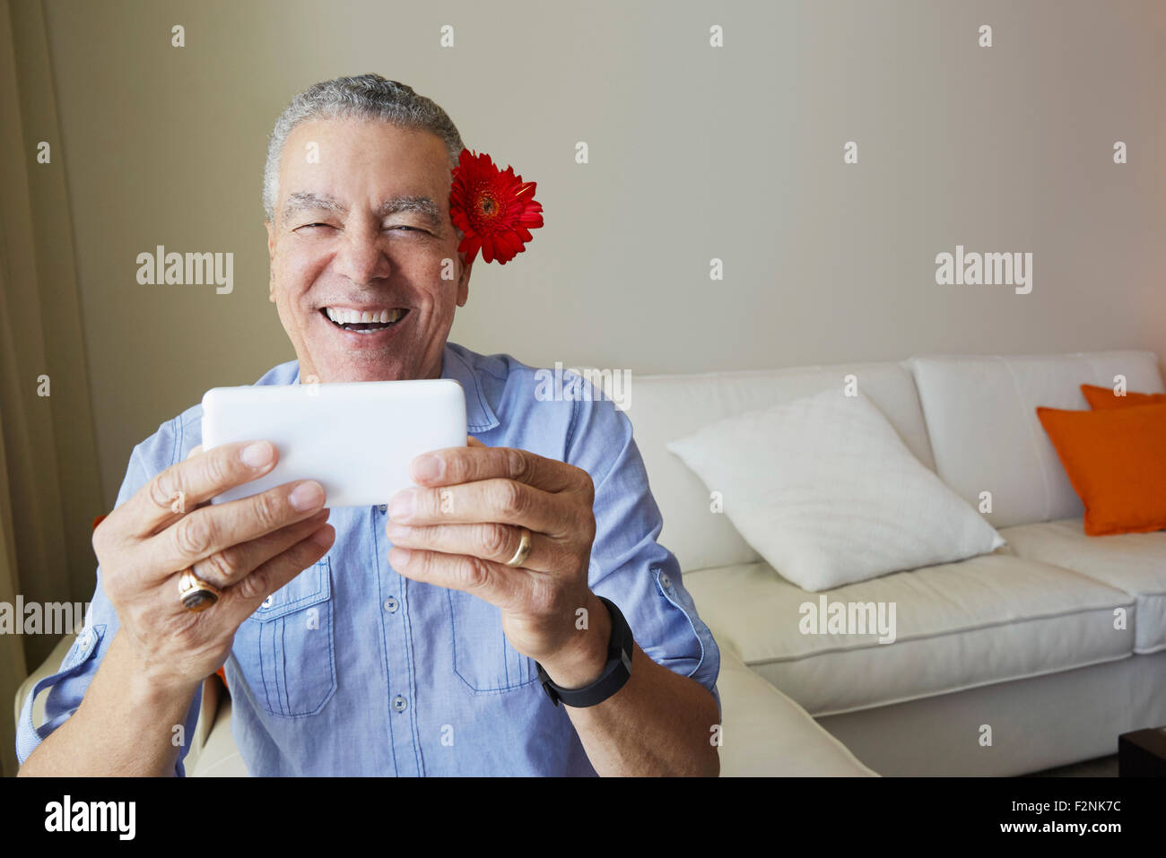 Vecchio Uomo nero tenendo selfie con fiore dietro il suo orecchio Foto Stock