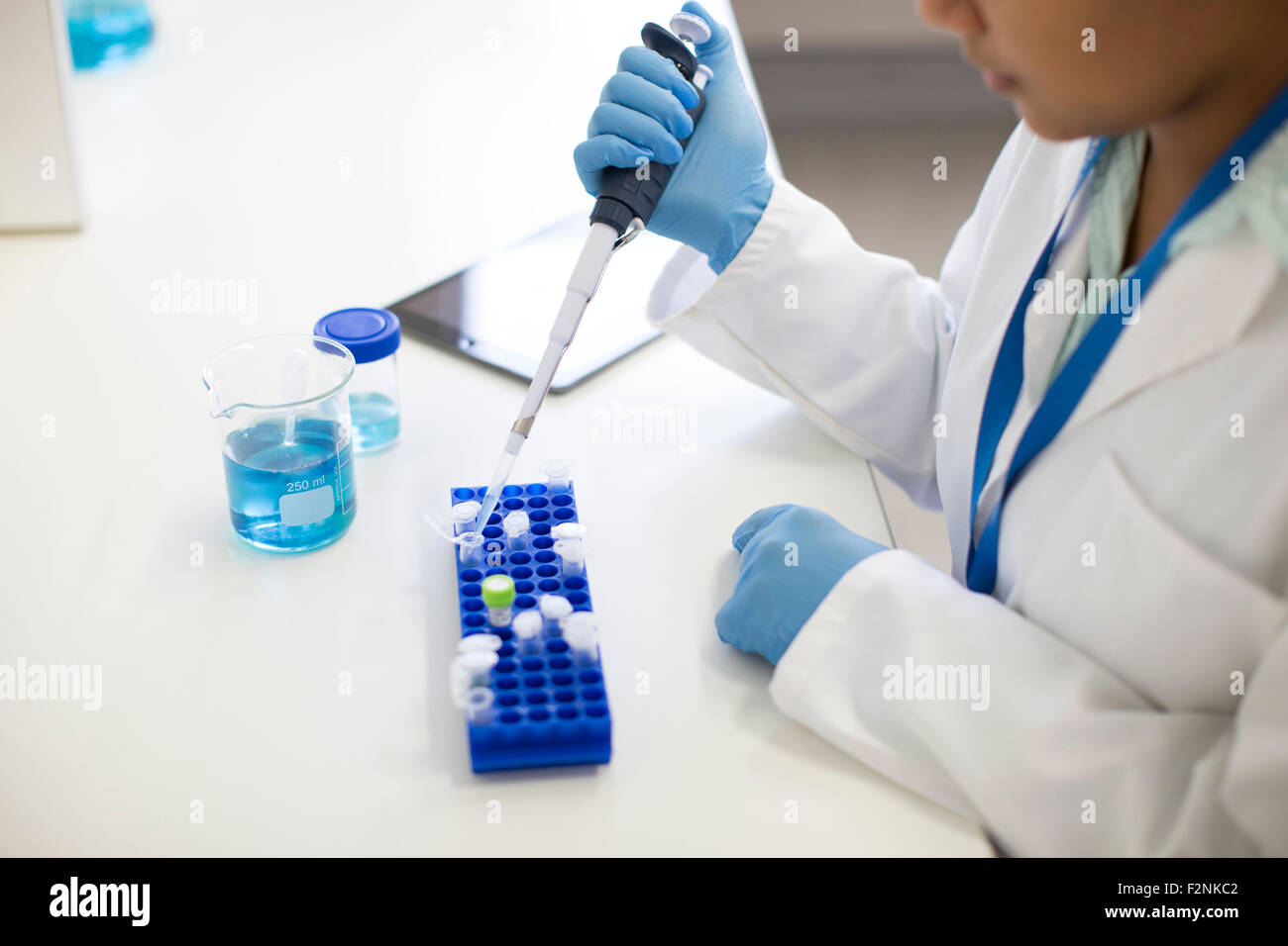 Razza mista scienziato il pipettaggio di campione nella provetta in laboratorio Foto Stock