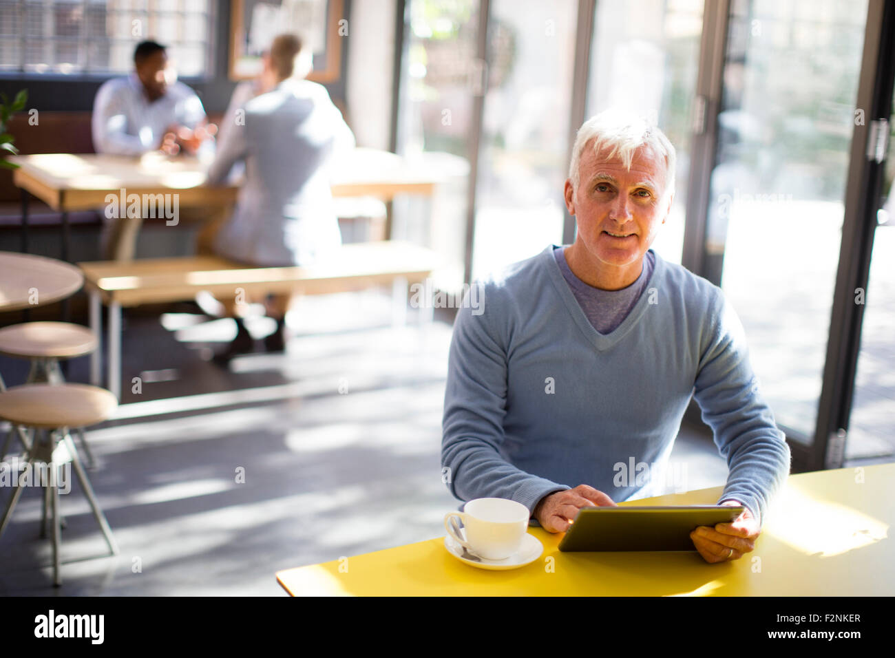 Uomo anziano con tavoletta digitale in cafe Foto Stock