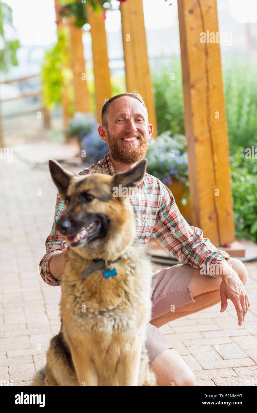 Uomo caucasico petting cane sul patio Foto Stock