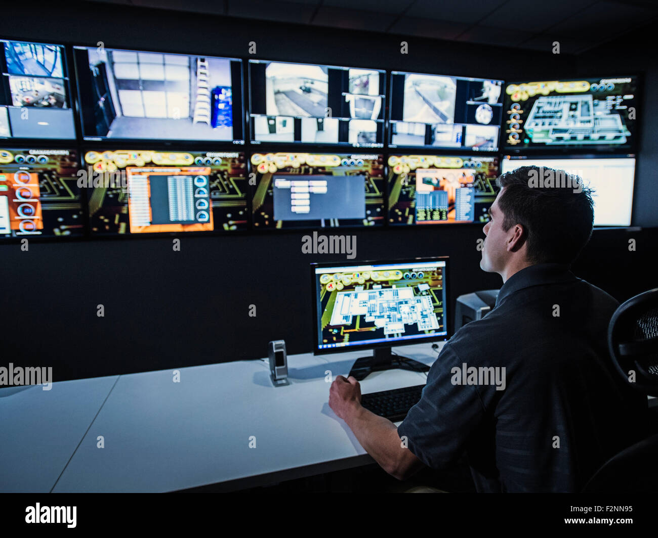 Ispanico guardia di sicurezza a guardare i monitor in sala di controllo Foto Stock