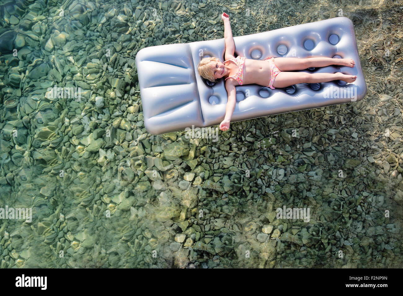 Ragazza caucasica galleggiante su zattera nel lago Foto Stock