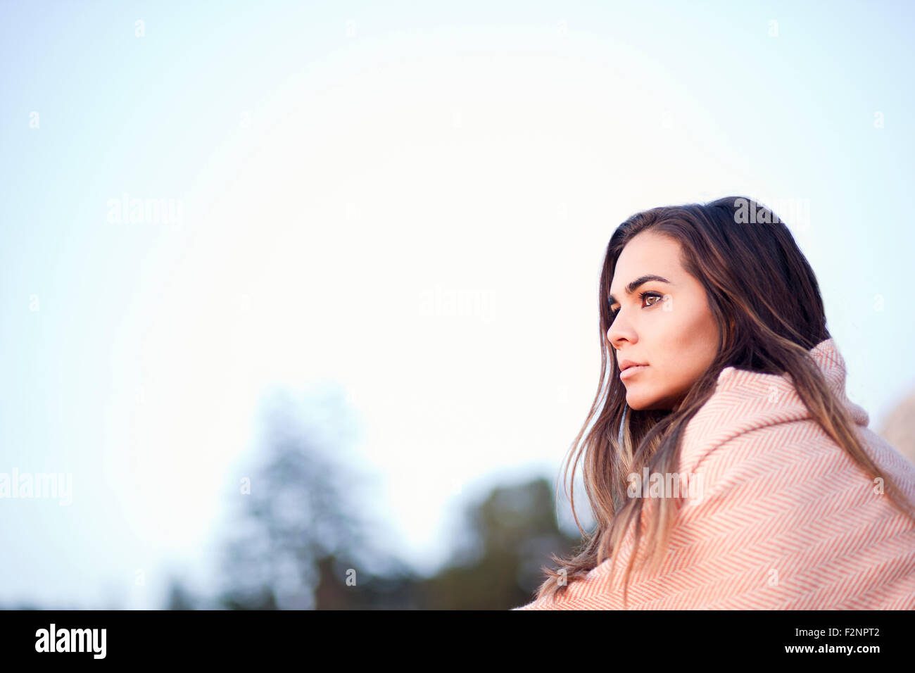 Razza mista donna avvolta in una coperta sotto il cielo blu Foto Stock