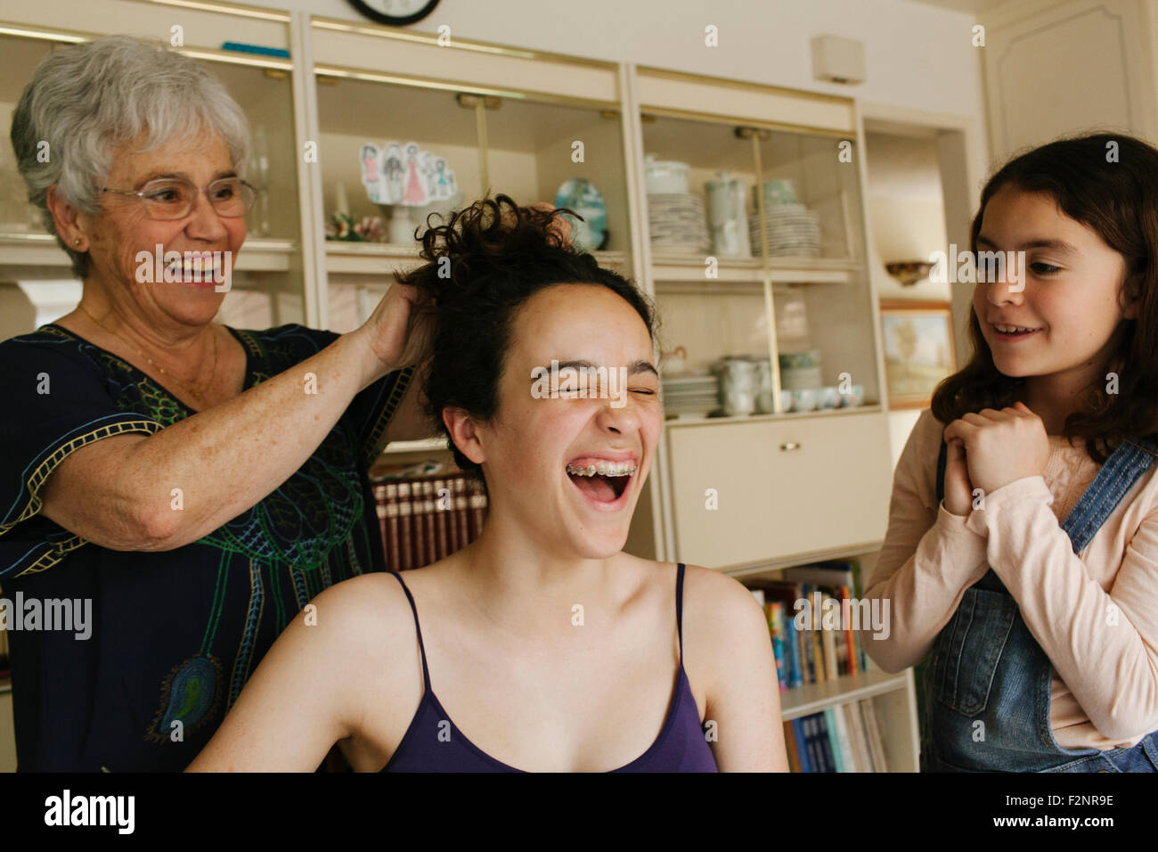 Nonna per lo styling dei capelli del nipote in sala da pranzo Foto Stock