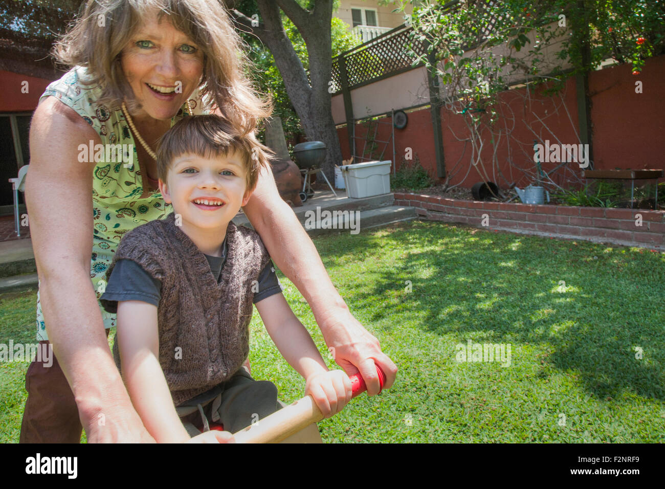 Nonna caucasica e nipote di bicicletta equitazione in cortile Foto Stock