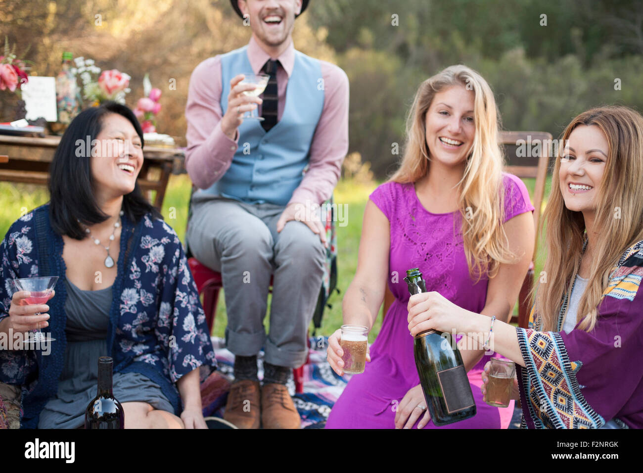 Gli amici a bere champagne a picnic nel parco Foto Stock
