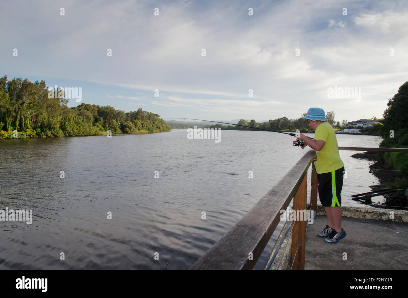 Un ragazzo giovane che pesca accanto ad un fiume nel NSW, Australia Foto Stock